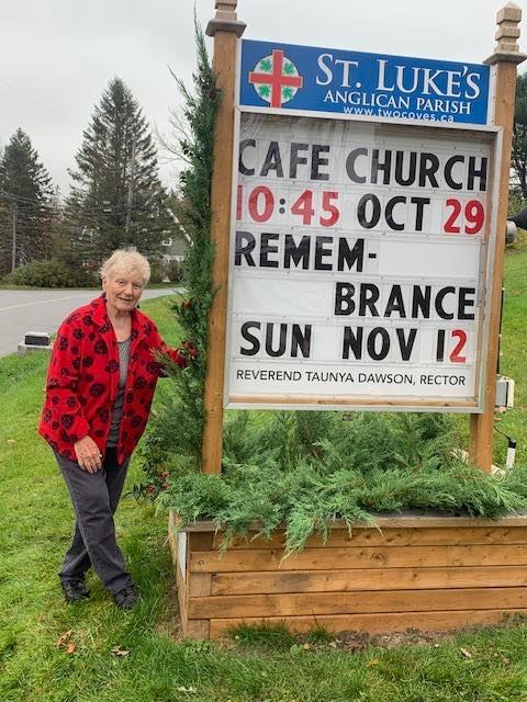 Catherin Chandler pauses after decorating the parish sign with greenery from Bill MacDonald's cedars and Ned Norwood's holly.